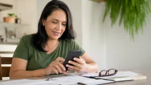 Trabalhadora consulta o lucro do FGTS 2026 pelo celular